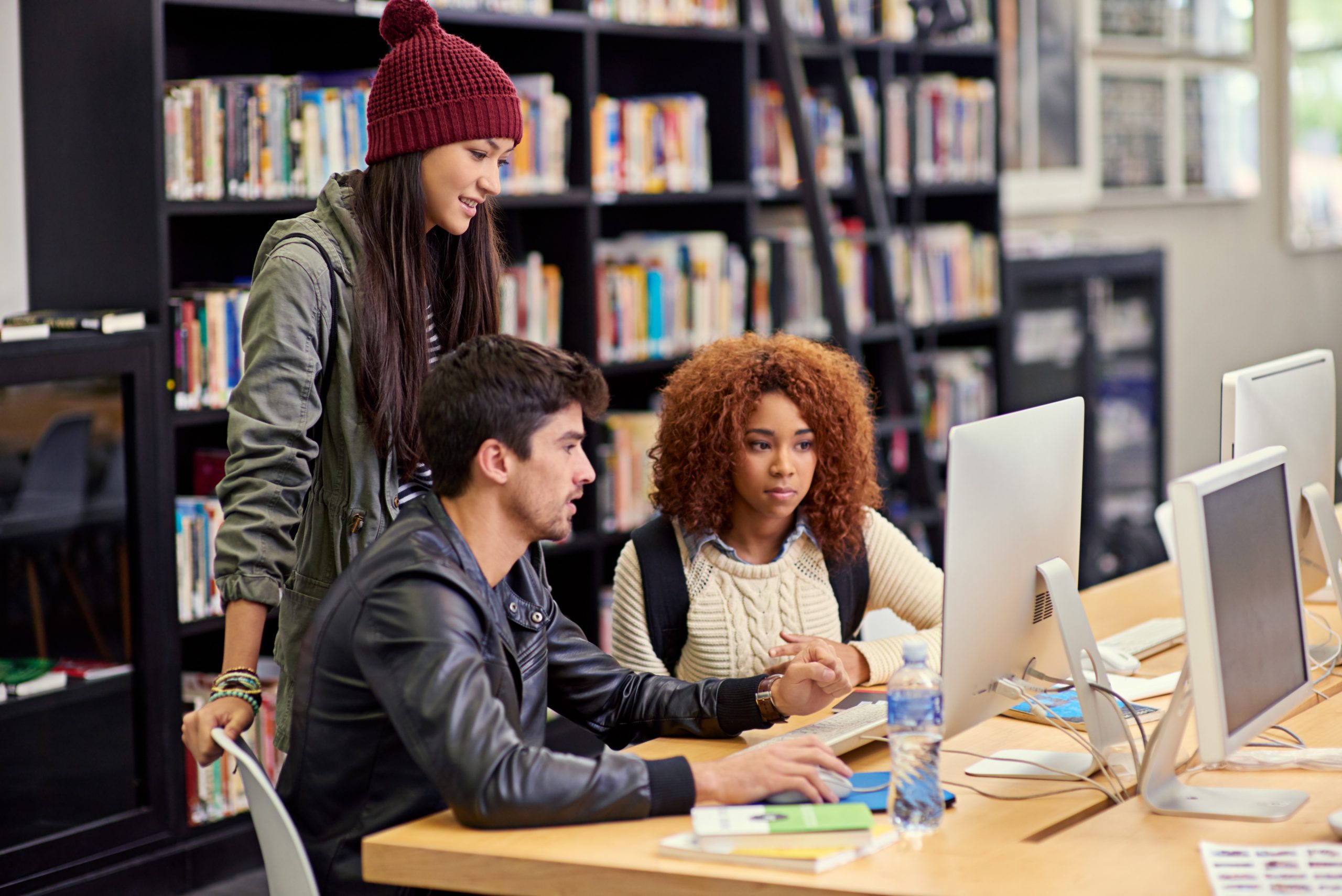 a group of students working together at a computer in a university library.